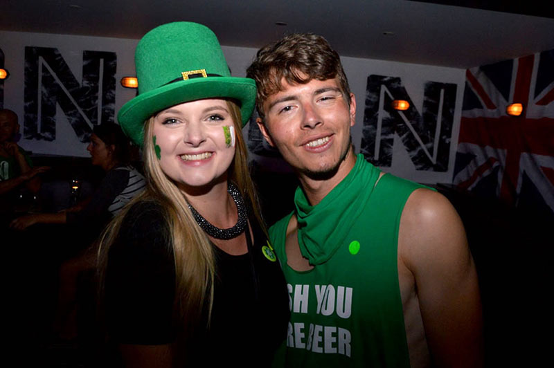 Irish couple on St Patrick's day pub crawl in Queenstown dressed in their best Irish green gear with hats and clover face paint