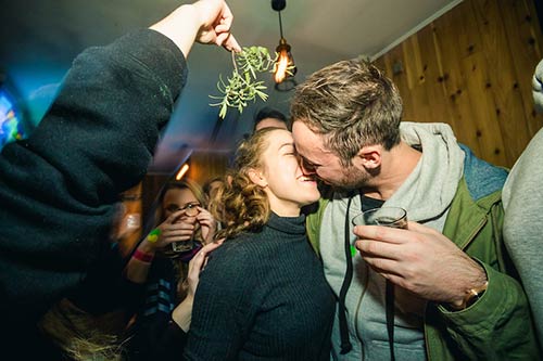 Man and woman kiss under mistletoe at a Christmas party in Queenstown