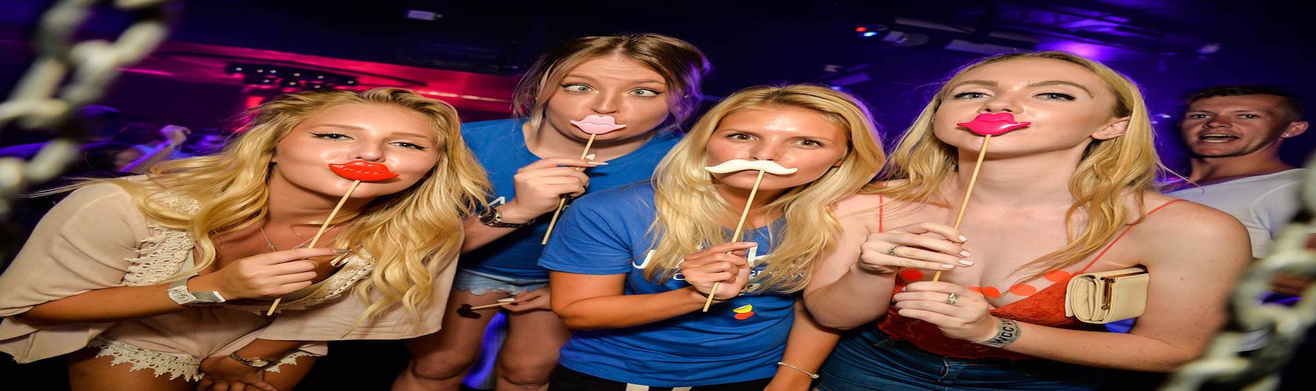 Group of girls on pub crawl holding funny props to their mouths
